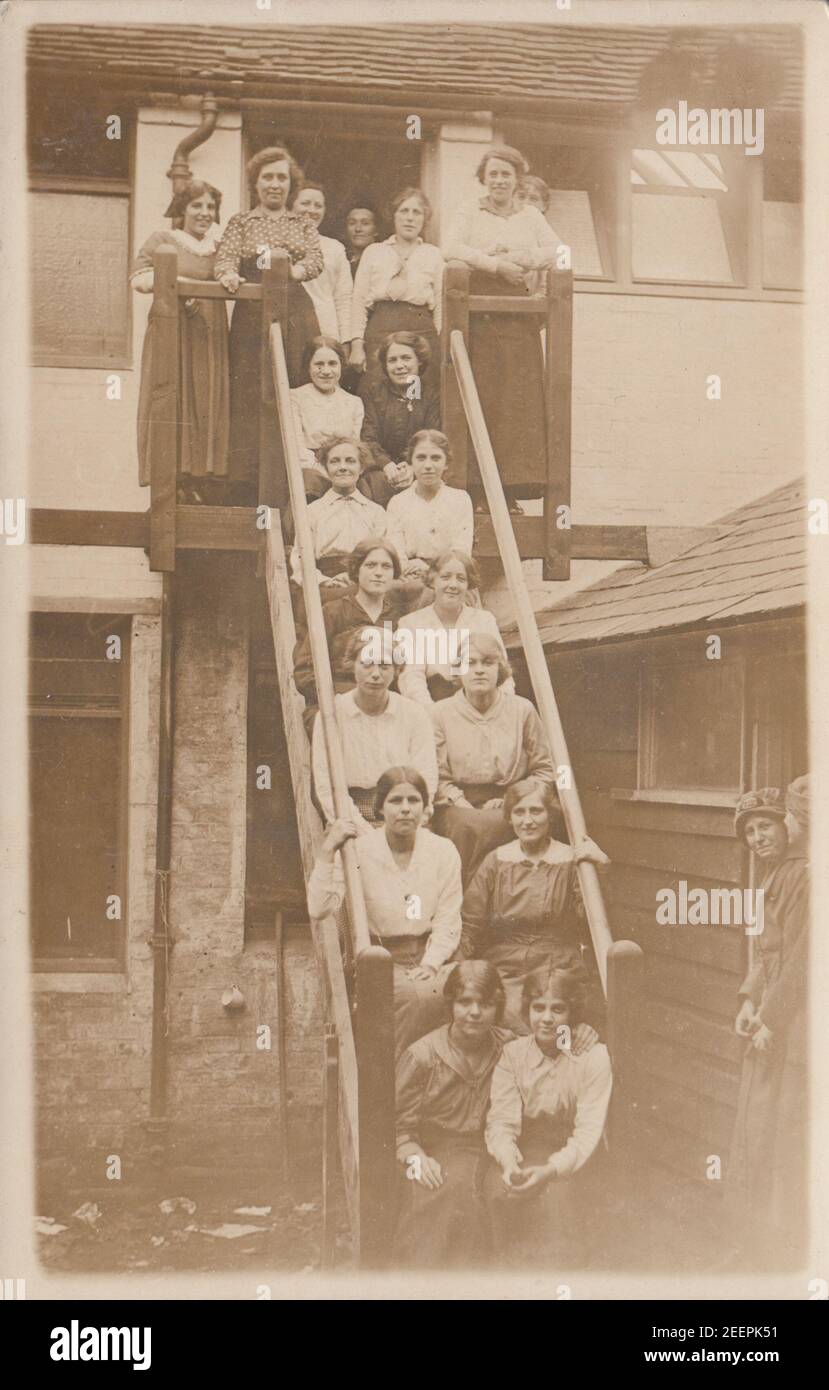 Vintage Anfang 20th Jahrhundert fotografische Postkarte zeigt eine Gruppe von weiblichen Arbeitern Sat auf Outdoor-Stufen. Stockfoto