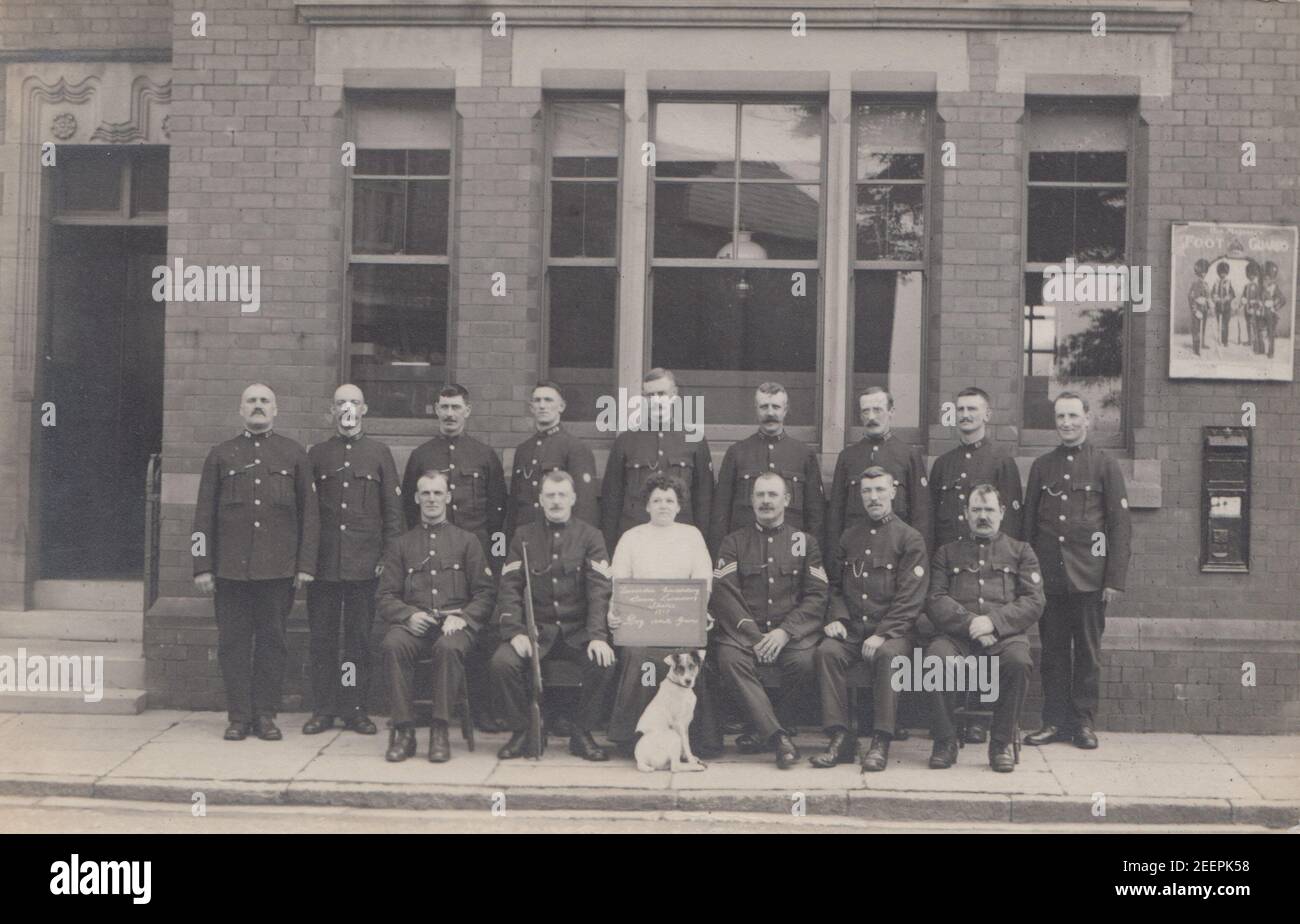 Vintage Fotopostkarte aus dem frühen 20. Jahrhundert mit einer Gruppe von Polizisten, einer Dame und einem Hund. Die Dame hält ein Schild mit der Aufschrift „Lancashire Constabulary, ????? Arbeiter schlagen 1913, Hund und Waffe Stockfoto