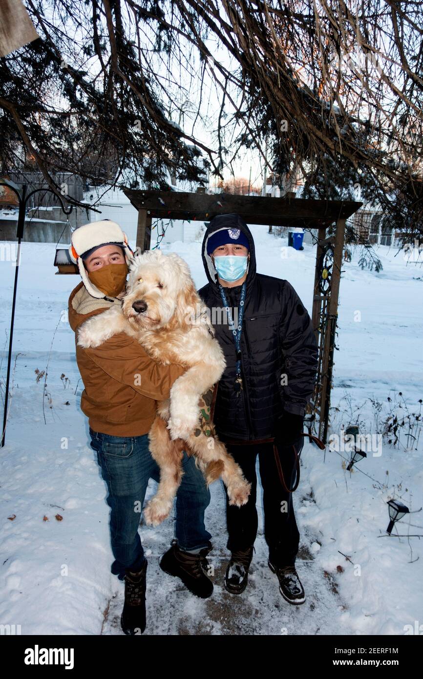 Brüder mit ihrem Golddoodle Haustier Hund kommen, um Oma und Opa draußen in Masken während der Covid Pandemie zu besuchen. St. Paul Minnesota, USA Stockfoto