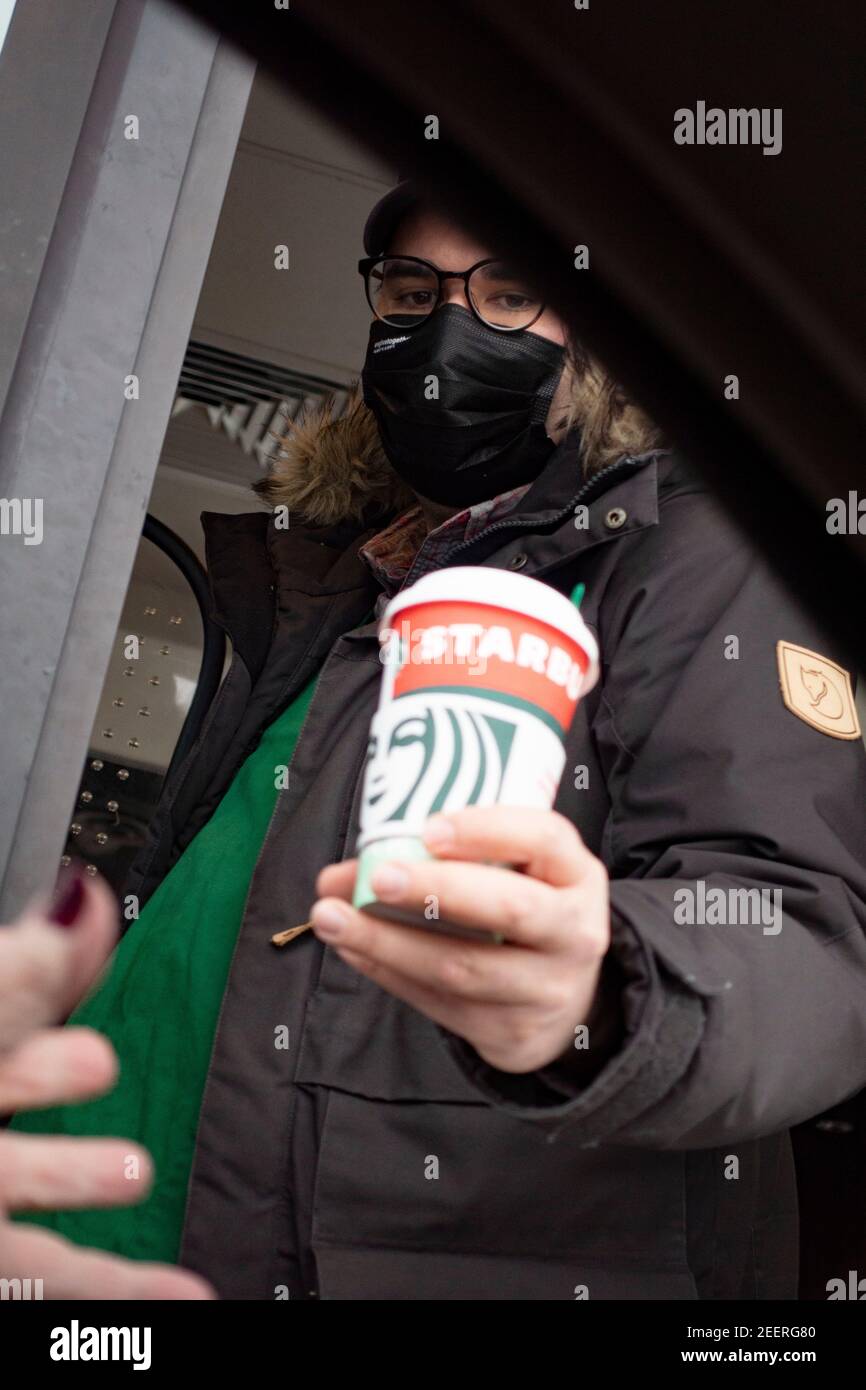 Maskierter Kaffeeservice, der einem Gast im Starbucks Drive-Thru eine Tasse in einem Auto überreicht. St. Paul Minnesota, USA Stockfoto