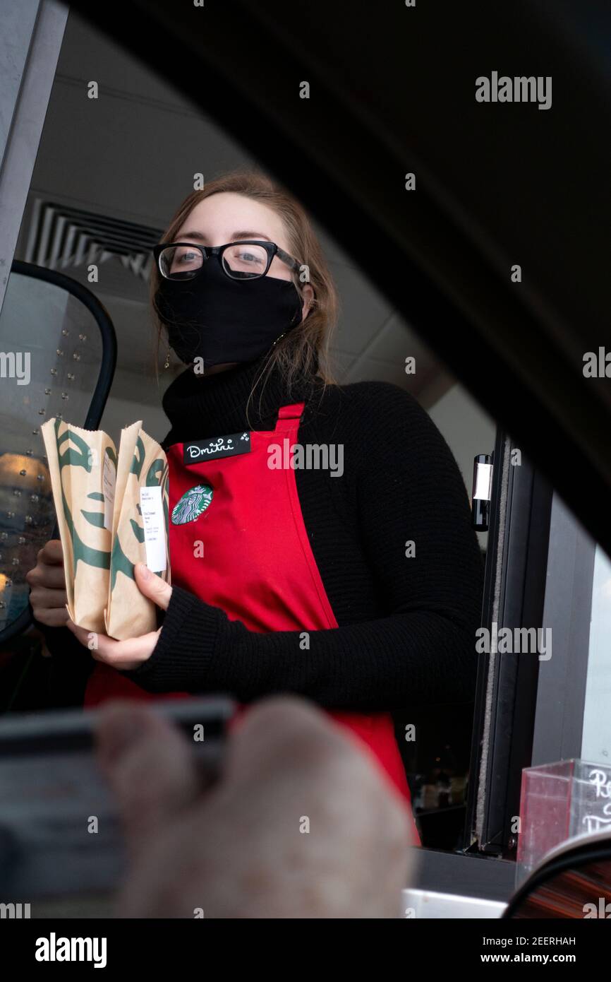 Der Kaffeeserver hat während der Covid Pandemie beim Starbucks Drive-Thru Backwaren in der Gästebox verteilt. St. Paul Minnesota, USA Stockfoto