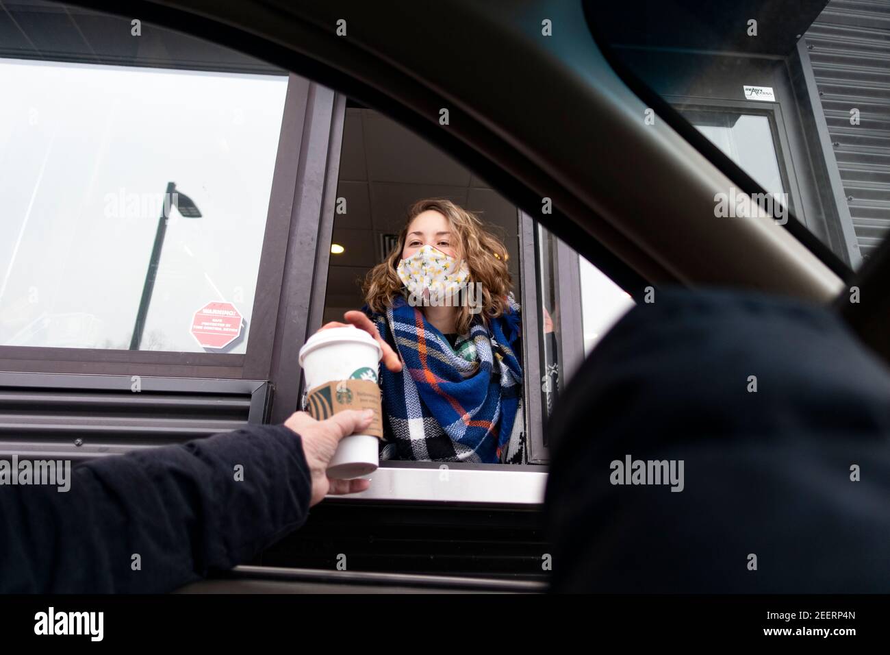 Maskierter Starbucks Drive-Thru-Kaffeeservice, der einem Gast im Auto während der Covid-Pandemie einen Kaffee überreicht. St. Paul Minnesota, USA Stockfoto