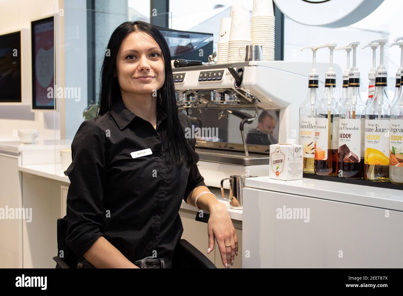 MINSK, WEISSRUSSLAND - Januar 2021: Inklusion mit Behinderung arbeitet als Barista in einem inklusiven Café. Der Barista bereitet bei der Arbeit in seinem Café Kaffee zu. Ein einzigartiges Projekt, ein inklusives Café. Ein Ort, an dem alle Mitarbeiter behindert sind. Wird von einer Person mit Down-Syndrom verwaltet. Alle Baristas sind deaktiviert. Daria Sacharenkova. 29 Jahre. Durch Ausbildung, einen Logistiker, durch Beruf, einen Barista. Im Alter von 25 Jahren kam sie in einen Autounfall und bekam eine Rückenmarksverletzung, so dass sie in einem Rollstuhl bewegt. In seiner Freizeit beschäftigt er sich mit Krafttraining, Ballsaal-Tanz im Rollstuhl und Blogs auf Instagram Stockfoto