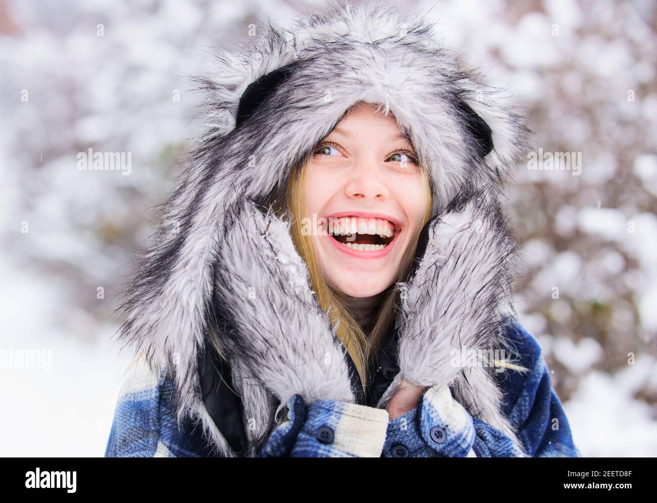 Winterzeit. Lächelndes Mädchen im Schneepark. Schöne junge Frau im Winter. Schönes Weibchen in warmem Mantel und Pelzhut. Stockfoto