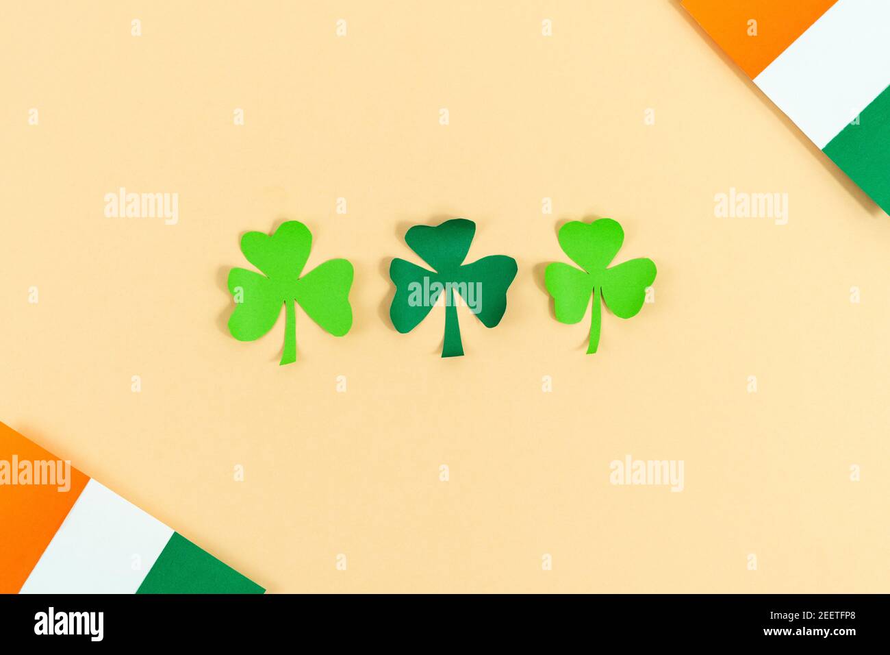 St. Patrick's Day. Drei Kleeblätter mit irischen Fahnen auf cremefarbenem Hintergrund. Speicherplatz kopieren. Draufsicht. Stockfoto
