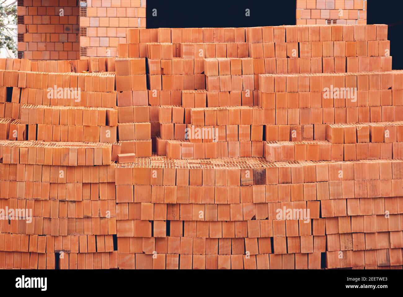 Lehmziegel Baumaterial und Gebäude im Bau im Hintergrund. Stockfoto