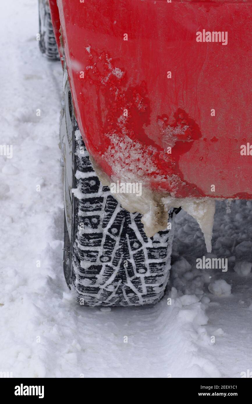 Eiszapfen am hinteren Kotflügel rot Auto im Winter. Spiked Reifen für Schnee fahren. Fahrkonzept bei kaltem und schlechtem Wetter. Stockfoto