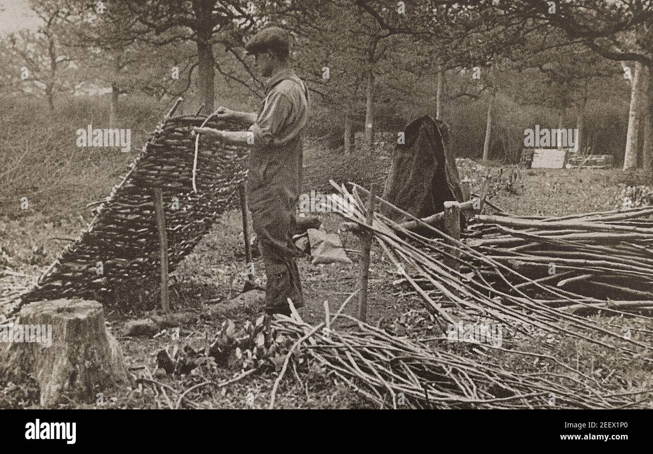 Ein altes Pressefoto eines britischen Waldarbeiters, der den letzten Stab einer handgewebten Wasserschleuderhürde (ca. 1940) fertigstellte ---- . Das Handwerk der Herstellung von beweglichen Wattle Hürden und Tore verwendet werden, um Teile eines Feldes abzubauen usw. oder für den Einsatz als Zaun ist eine Aufgabe, die weit zurück in die Geschichte reicht. Obwohl viele Bauern ihre eigenen machen würden, haben Waldarbeiter sie heute in Großbritannien als Beruf von Hand hergestellt und noch immer hergestellt. Überreste neolithischer und eisenzeitlicher Weiden- und Hasel-Hürden wurden von Archäologen in Sumpfgebieten in ganz Großbritannien gefunden Stockfoto