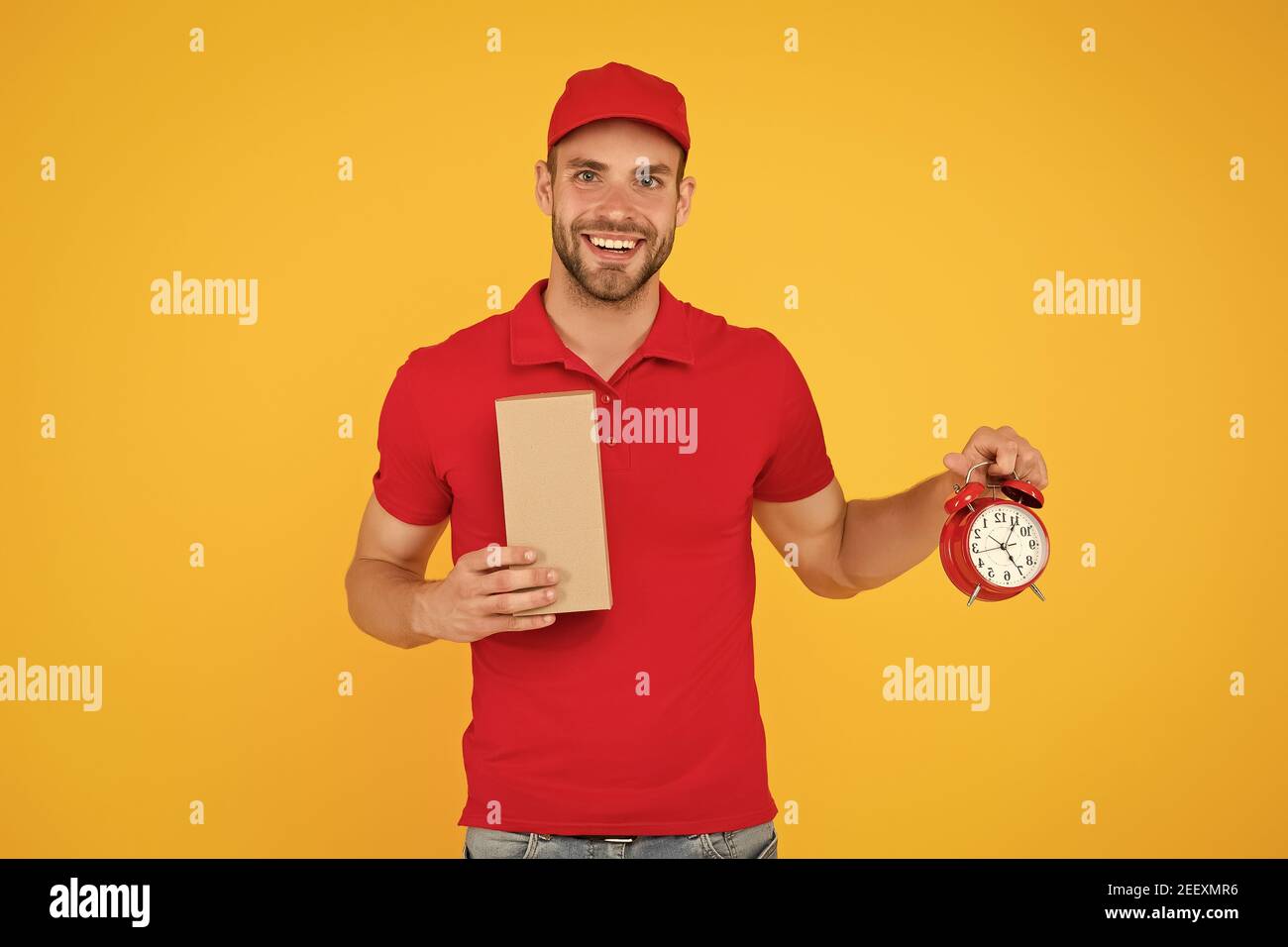Echte Freude. Gehen Sie online einkaufen. Lieferung während der Quarantäne. Freundliche Mitarbeiter Mann. Lieferzeit. Lieferung Kurier mit Zeit Uhr Haltekasten. Nehmen Sie Ihr Paket. Geschenk Lieferung Mann mit Vintage Uhr. Stockfoto