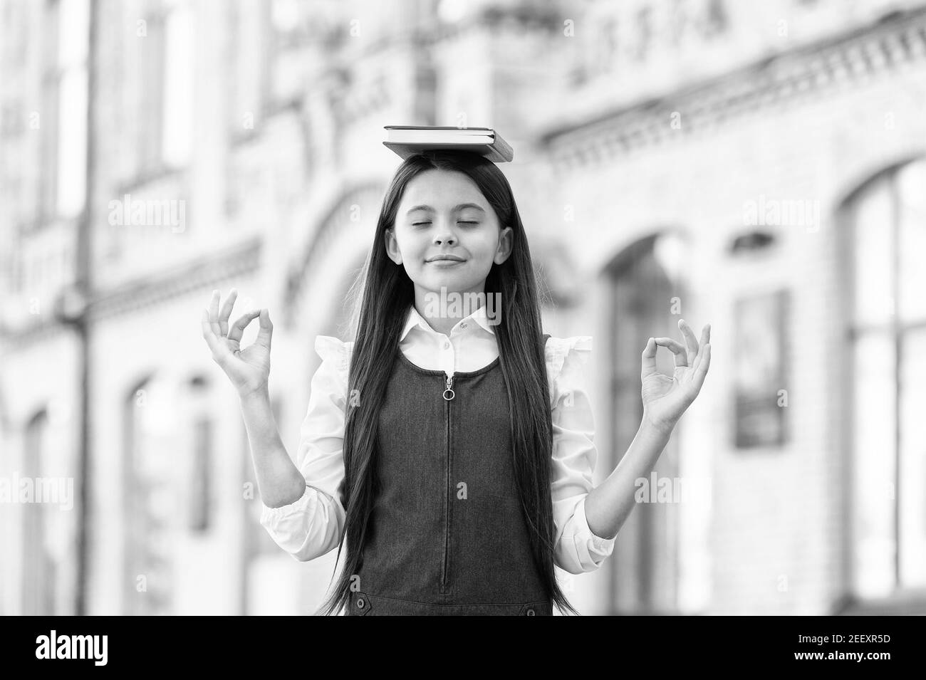 Beruhigen Sie den Geist. Kleines Kind meditieren im Freien. Kleines Mädchen tun mudra Hände halten Buch auf dem Kopf. Meditation für geistiges Gleichgewicht. Meditationskurs für Anfänger. Schule und Bildung. Beste Therapie. Stockfoto