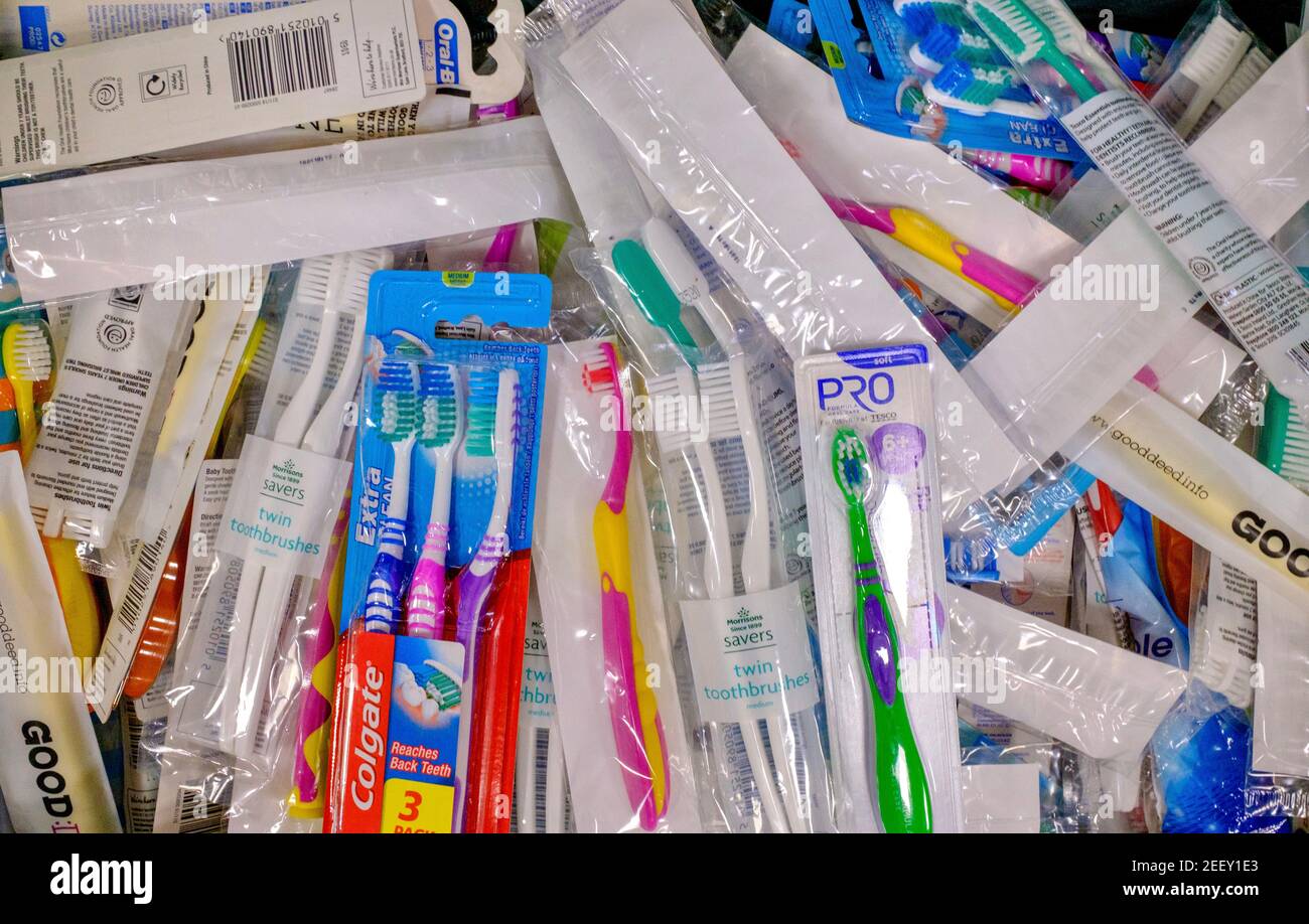 Eine Kiste Zahnbürsten in Kunststoffverpackung, die einer Trussell Trust Foodbank für die Oralhygiene gespendet wurde. Eine Reihe von Handzahnbürsten und -Marken. Stockfoto