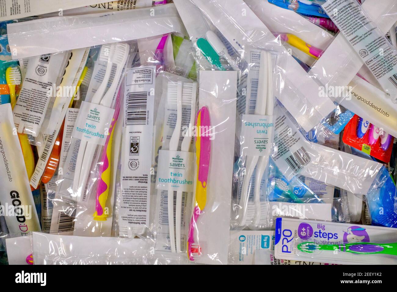 Eine Kiste Zahnbürsten in Kunststoffverpackung, die einer Trussell Trust Foodbank für die Oralhygiene gespendet wurde. Eine Reihe von Handzahnbürsten und -Marken. Stockfoto