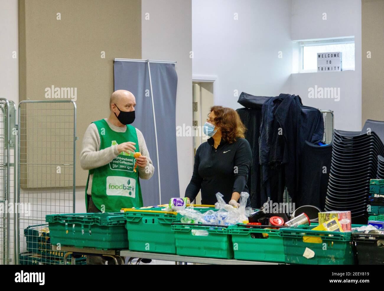 Zwei Freiwillige bei einer Trussell Trust Foodbank in Colindale, London, diskutieren über Nahrungsmittelspenden für Nahrungsmittelnotpakete zur Bekämpfung der Lebensmittelarmut. VEREINIGTES KÖNIGREICH. Stockfoto