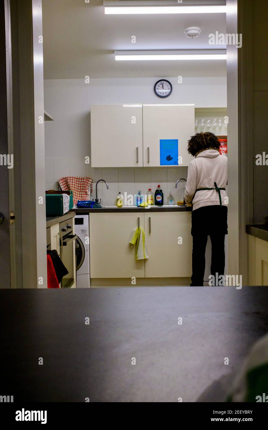 Eine Frau spült Töpfe und Geschirr in einer Küche. Fairy Liquid sichtbar neben dem Waschbecken. Stockfoto