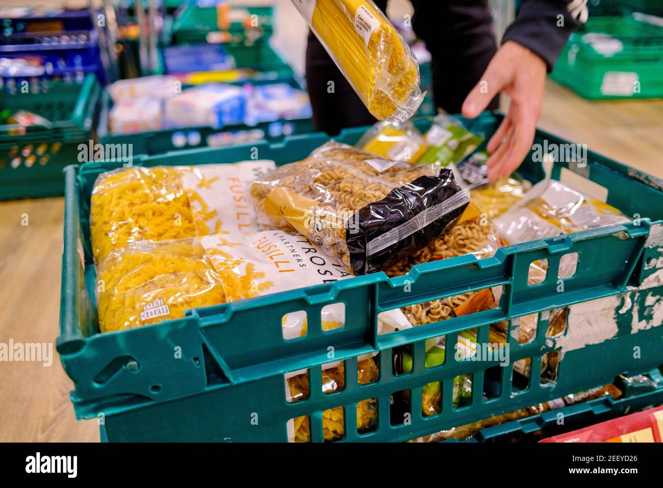 Eine freiwillige Lebensmittelbank nimmt Päckchen Pasta in einer Kiste mit Lebensmittelspenden in einer Trussell Trust Foodbank auf. Essential Waitrose Eigenmarke. Stockfoto