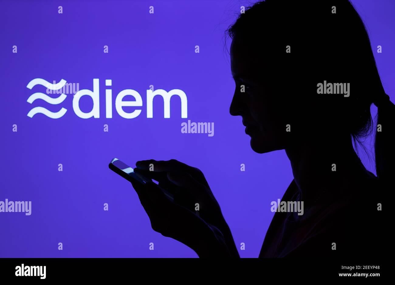 Silhouette eines Mädchens mit Smartphone und Facebook Diem Kryptowährung Logo auf dem verschwommenen Bildschirm. Echtes Foto, keine Montage, keine Nachbearbeitung. Stafford Stockfoto