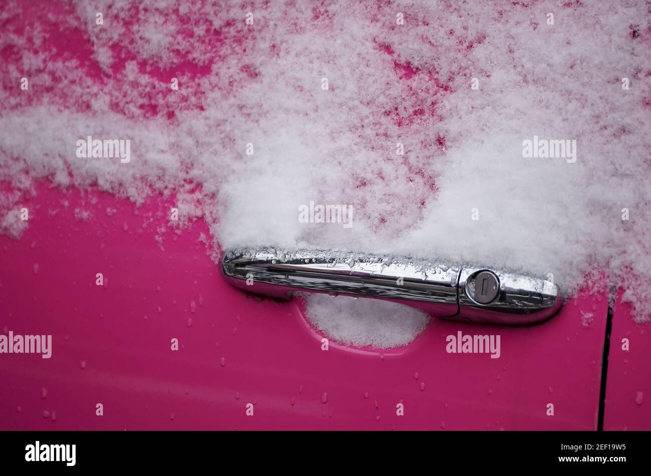 Bukarest, Rumänien - 17. März 2021: Der Türgriff eines rosafarbenen Autos ist gefroren und voller Schnee. Stockfoto