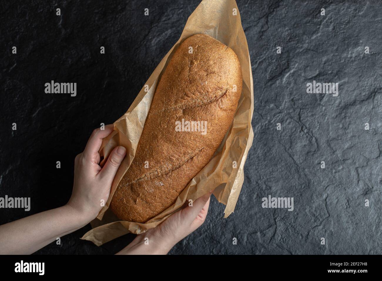 Frau hält eingewickeltes frisches Brot mit ihren Händen Stockfoto