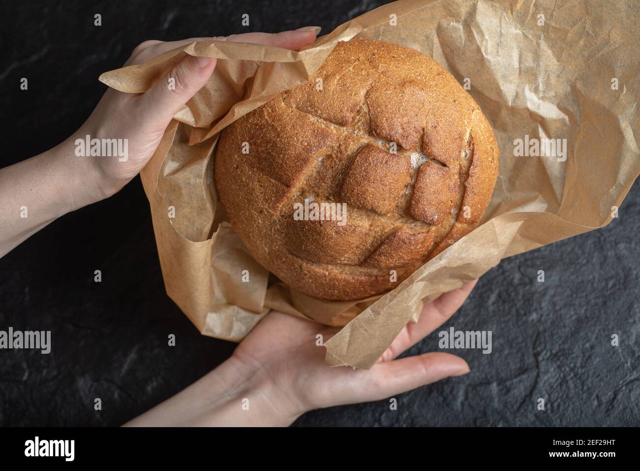 Frau entpacken frisch gebackenes Roggenbrot mit ihren Händen Stockfoto