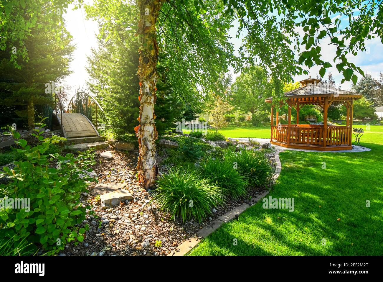 Ein schön gestalteter Garten und Hinterhof mit einem runden Zedernholz Pavillon und eine Brücke über mehr Landschaftsgestaltung Bereiche. Stockfoto
