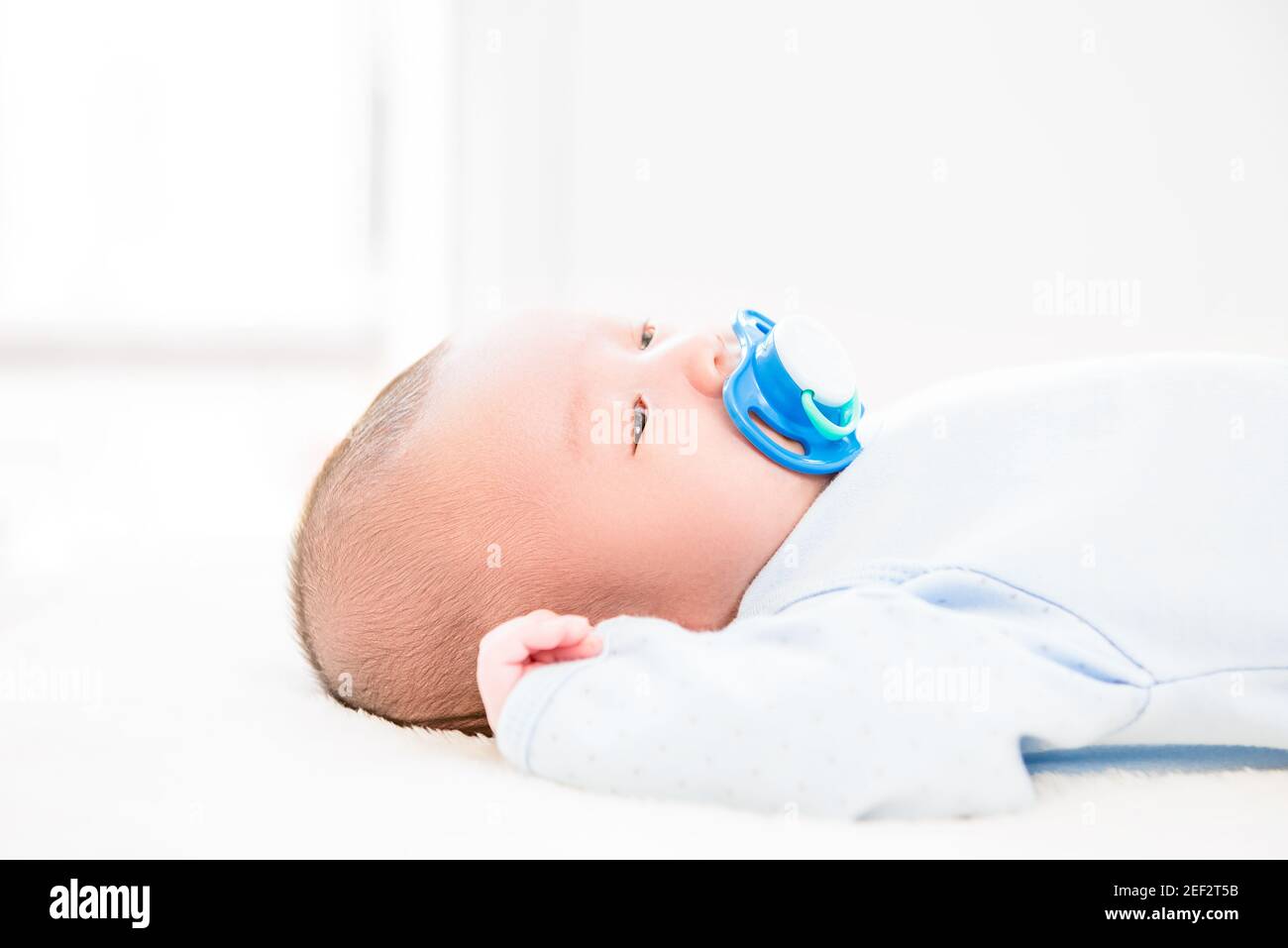 Liebenswert kleines neugeborenes Baby mit Dummy auf dem Bett liegen Stockfoto