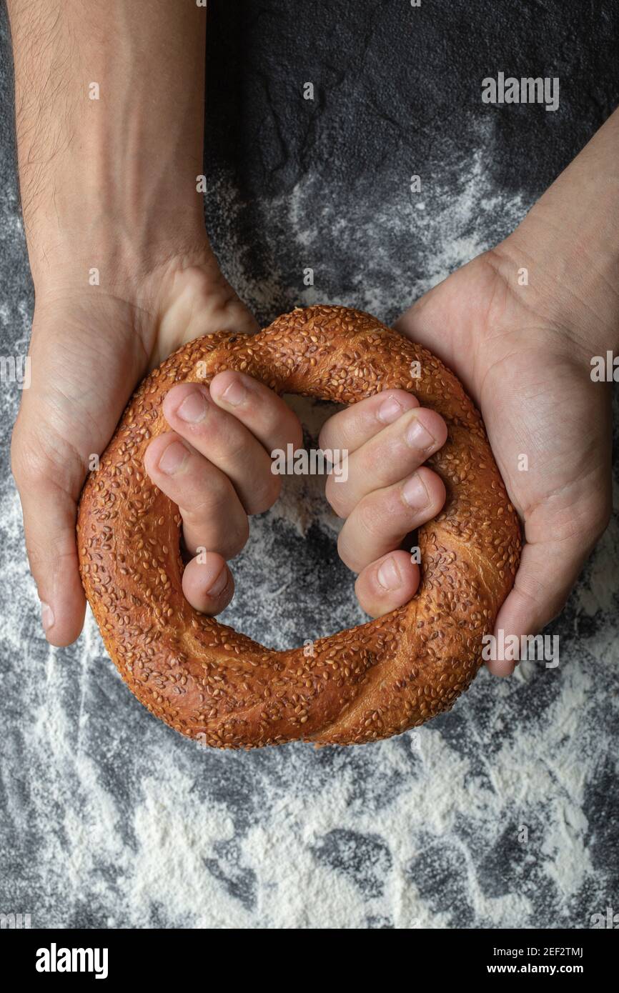 Vertikale Foto von Frau Hände halten frische türkische simit auf Platine Stockfoto