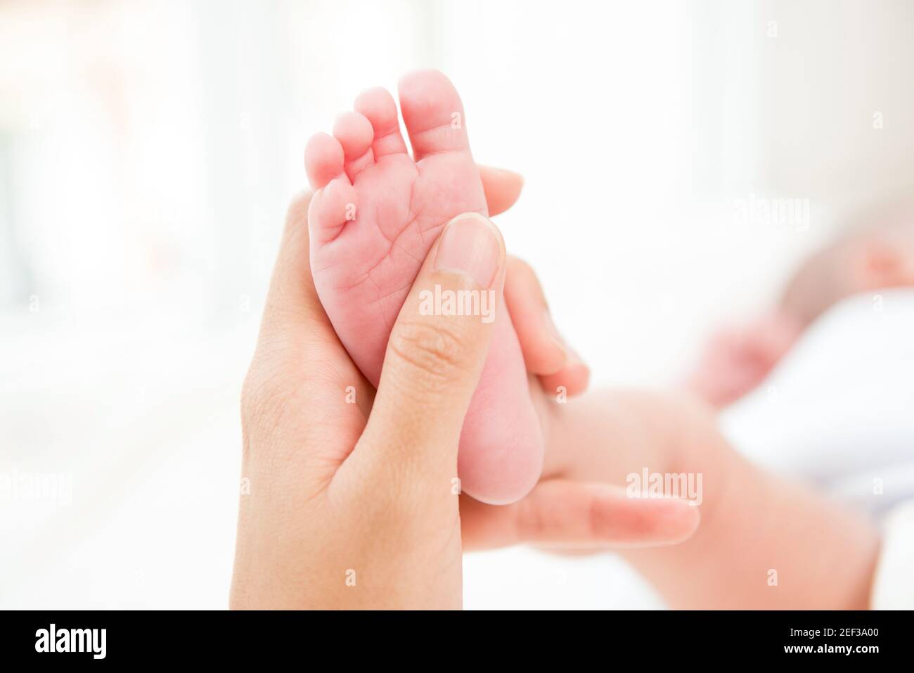 Mutter Hand sanft berühren kleinen Baby Fuß mit Sorgfalt Stockfoto