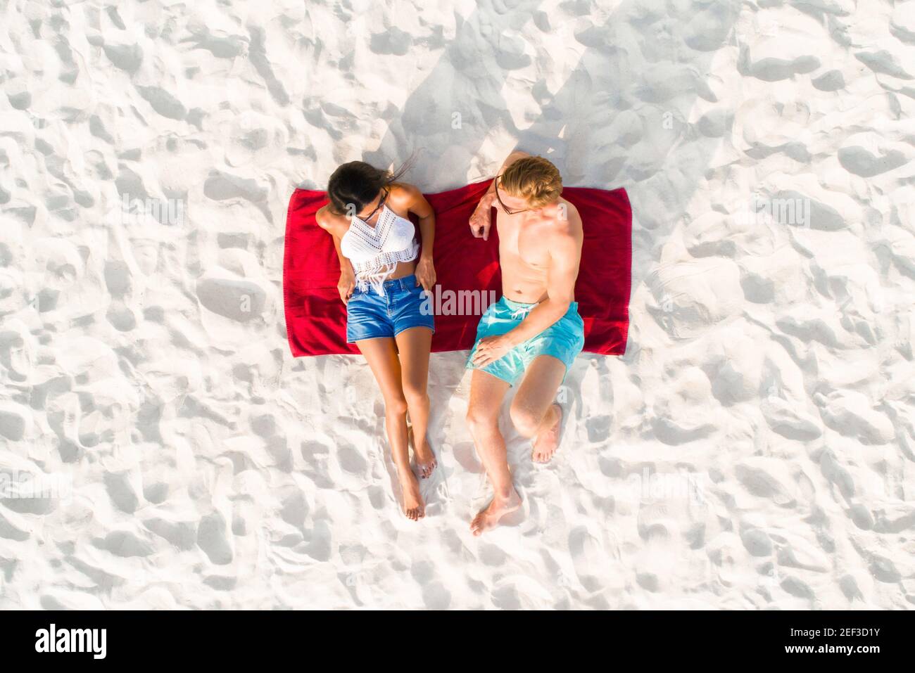 Blick von oben auf ein Paar, das am weißen Sandstrand liegt Ein Sonnenbad im Sommerurlaub Stockfoto Blick von oben auf ein Paar, das am weißen Sandstrand liegt Ein Sonnenbad im Sommerurlaub Stockfoto