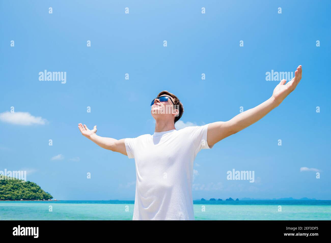 Junger Mann, der die Arme hebt, Palmen öffnet, im Sommer in die Luft am Strand blickt - Freiheit und Urlaubskonzepte Stockfoto Junger Mann, der die Arme hebt, Palmen öffnet, im Sommer in die Luft am Strand blickt - Freiheit und Urlaubskonzepte Stockfoto