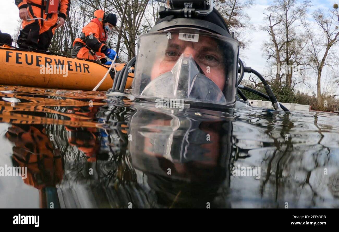 16. Februar 2021, Hessen, Frankfurt/Main: Feuerwehrmann Jochen Schneider vom Wasserrettungsteam der Feuerwehr Frankfurt am Main taucht bei einer Übung in ein Eisloch auf dem gefrorenen Ostpark-Teich. Das Eis auf gefrorenen Seen und Teichen ist verlockend - kann aber trotz seiner scheinbaren Stabilität lebensbedrohlich sein. Um dann helfen zu können, müssen auch die Taucher der Feuerwehr Rettungseinsätze trainieren. In diesem Winter sind die Bedingungen dafür richtig. (To dpa 'Eisrettung als Trainingsfall - eine Premiere für junge Feuerwehrleute') Foto: Arne Dedert/dpa Stockfoto