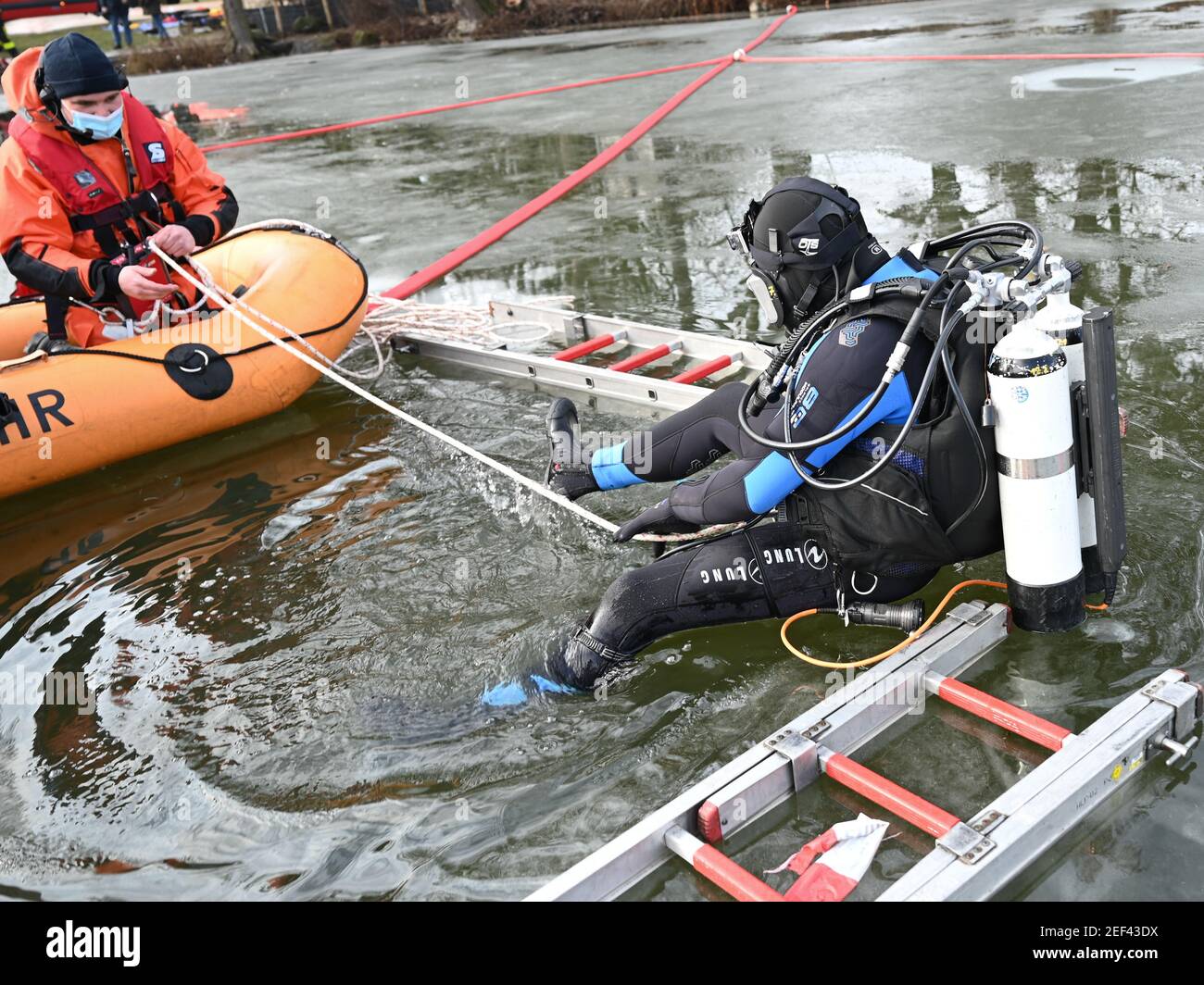 16. Februar 2021, Hessen, Frankfurt/Main: Feuerwehrmann Julian Böhmecke (r) von der Wasserrettungsstelle der Feuerwehr Frankfurt am Main nimmt an einer Übung in einem Eisloch auf dem gefrorenen Ostpark-Teich Teil. Das Eis an gefrorenen Seen und Teichen ist verführerisch - kann aber trotz seiner scheinbaren Stabilität lebensbedrohlich sein. Um dann helfen zu können, müssen auch die Taucher der Feuerwehr Rettungseinsätze trainieren. In diesem Winter sind die Bedingungen dafür richtig. (To dpa 'Eisrettung als Trainingsfall - eine Premiere für junge Feuerwehrleute') Foto: Arne Dedert/dpa Stockfoto