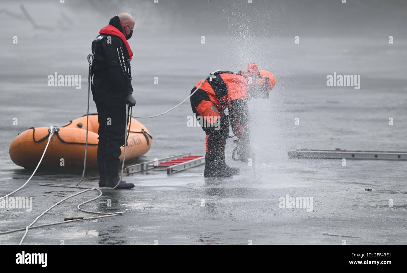 16. Februar 2021, Hessen, Frankfurt/Main: Ein Feuerwehrmann des Wasserrettungsteams der Feuerwehr Frankfurt am Main schneidet zu Beginn einer Tauchübung mit einer Kettensäge ein Loch in den gefrorenen Ostpark-Teich. Das Eis auf gefrorenen Seen und Teichen ist verlockend - aber trotz seiner scheinbaren Stabilität kann es lebensbedrohlich sein. Um in solchen Fällen helfen zu können, müssen die Taucher der Feuerwehr auch in Rettungseinsätzen trainieren. In diesem Winter sind die Bedingungen dafür richtig. (To dpa 'Eisrettung als Trainingsfall - eine Premiere für junge Feuerwehrleute') Foto: Arne Dedert/dpa Stockfoto