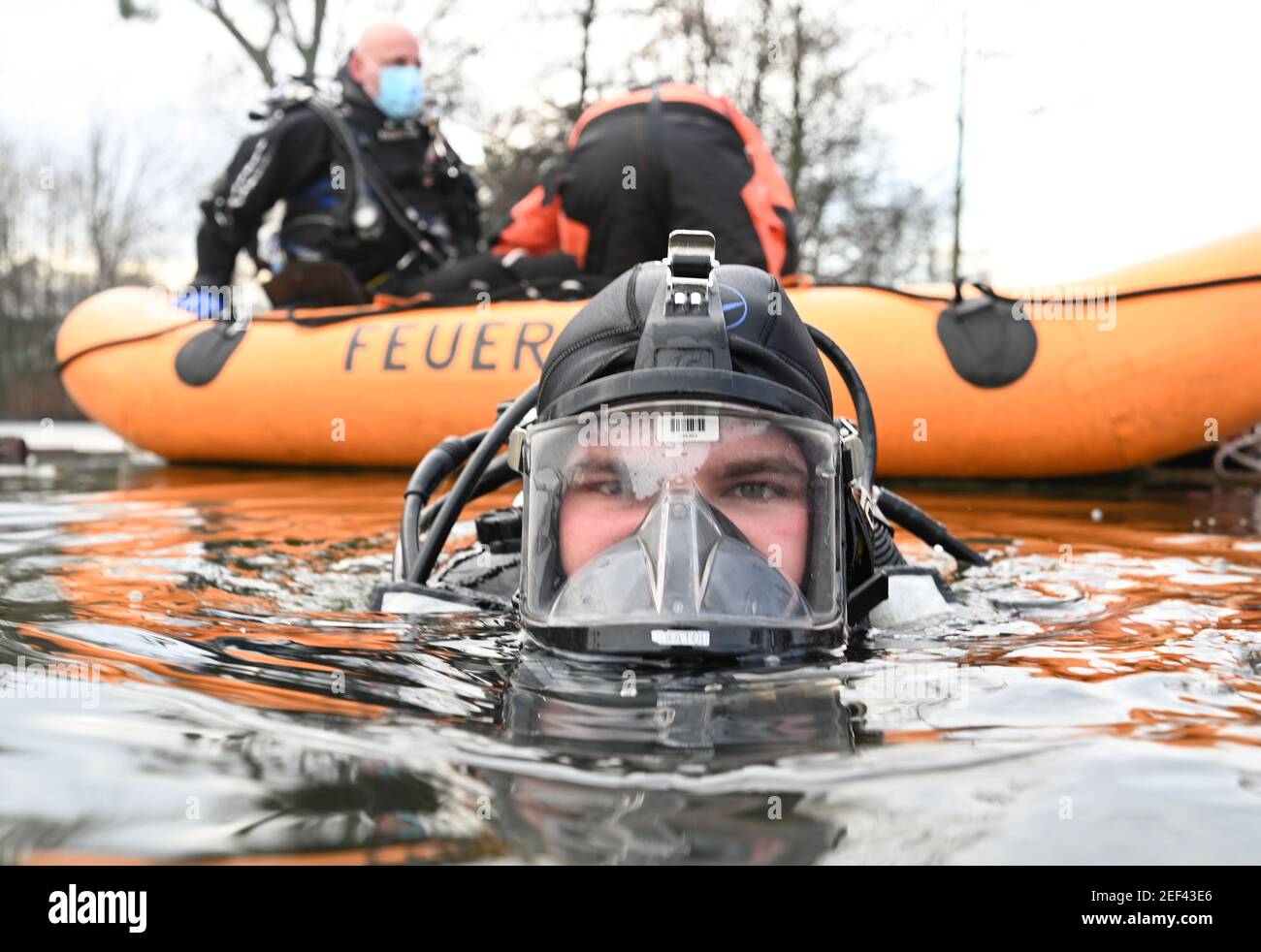 16. Februar 2021, Hessen, Frankfurt/Main: Feuerwehrmann Julian Böhmecke vom Wasserrettungsteam der Feuerwehr Frankfurt am Main taucht bei einer Übung in ein Eisloch auf dem gefrorenen Ostpark-Teich. Das Eis auf gefrorenen Seen und Teichen ist verlockend - kann aber trotz seiner scheinbaren Stabilität lebensbedrohlich sein. Um dann helfen zu können, müssen auch die Taucher der Feuerwehr Rettungseinsätze trainieren. In diesem Winter sind die Bedingungen dafür richtig. (To dpa 'Eisrettung als Trainingsfall - eine Premiere für junge Feuerwehrleute') Foto: Arne Dedert/dpa Stockfoto