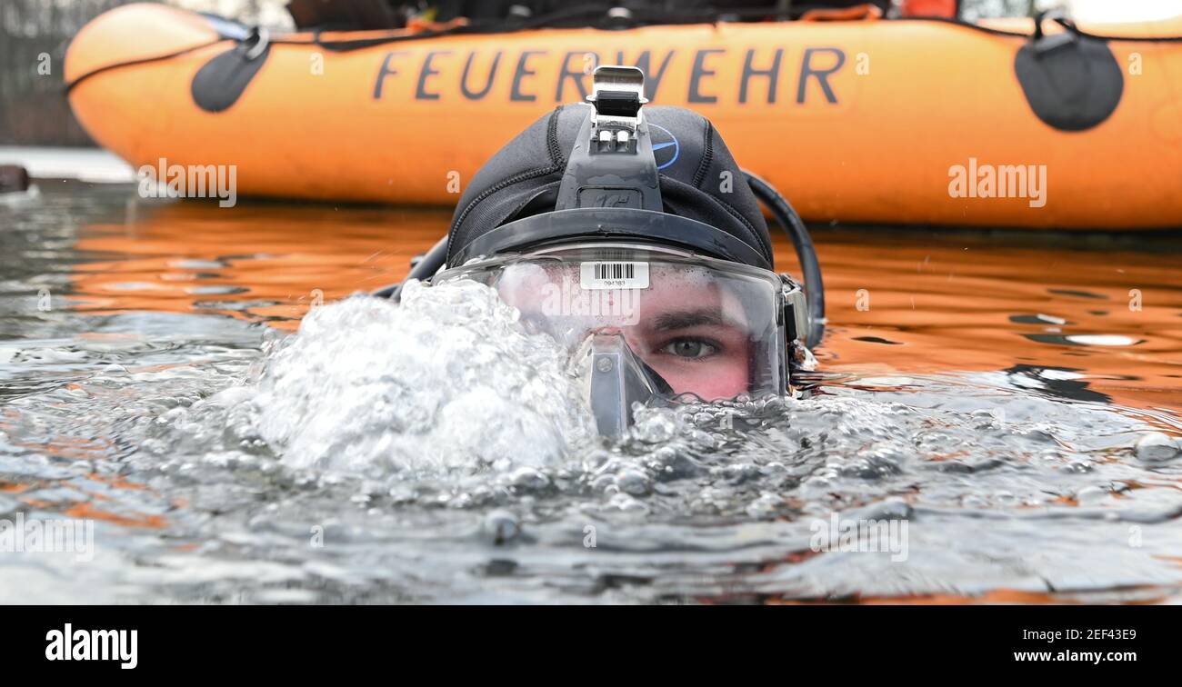 16. Februar 2021, Hessen, Frankfurt/Main: Feuerwehrmann Julian Böhmecke vom Wasserrettungsteam der Feuerwehr Frankfurt am Main taucht bei einer Übung in ein Eisloch auf dem gefrorenen Ostpark-Teich. Das Eis auf gefrorenen Seen und Teichen ist verlockend - kann aber trotz seiner scheinbaren Stabilität lebensbedrohlich sein. Um dann helfen zu können, müssen auch die Taucher der Feuerwehr Rettungseinsätze trainieren. In diesem Winter sind die Bedingungen dafür richtig. (To dpa 'Eisrettung als Trainingsfall - eine Premiere für junge Feuerwehrleute') Foto: Arne Dedert/dpa Stockfoto