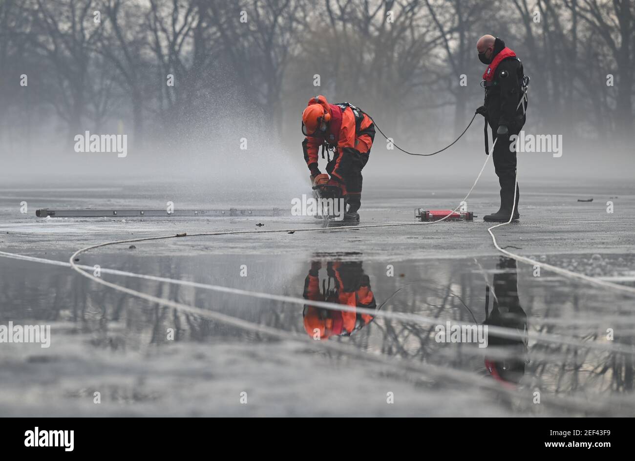 16. Februar 2021, Hessen, Frankfurt/Main: Ein Feuerwehrmann des Wasserrettungsteams der Feuerwehr Frankfurt am Main schneidet zu Beginn einer Tauchübung mit einer Kettensäge ein Loch in den gefrorenen Ostpark-Teich. Das Eis auf gefrorenen Seen und Teichen ist verlockend - aber trotz seiner scheinbaren Stabilität kann es lebensbedrohlich sein. Um in solchen Fällen helfen zu können, müssen die Taucher der Feuerwehr auch in Rettungseinsätzen trainieren. In diesem Winter sind die Bedingungen dafür richtig. (To dpa 'Eisrettung als Trainingsfall - eine Premiere für junge Feuerwehrleute') Foto: Arne Dedert/dpa Stockfoto