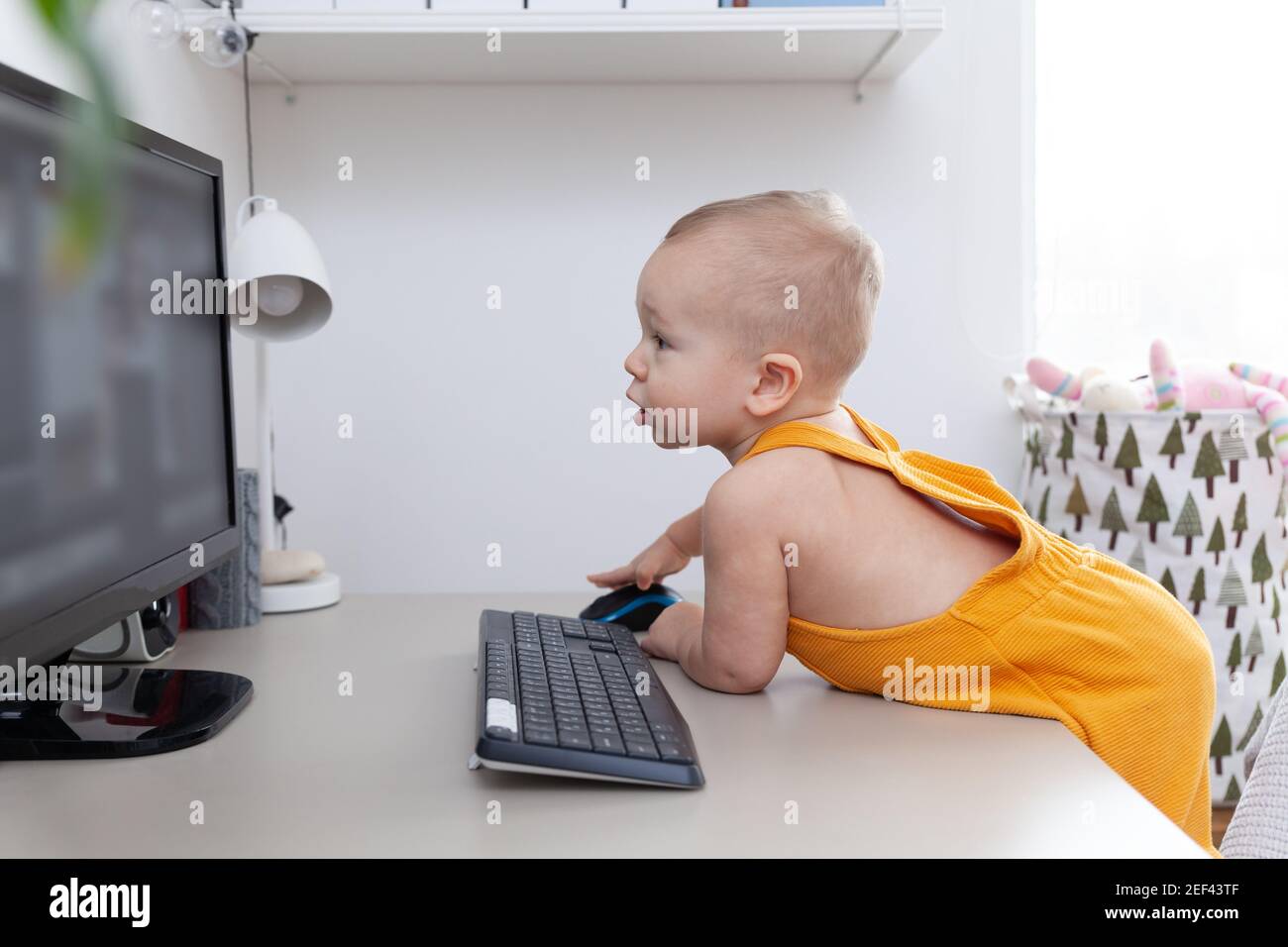 Kaukasischen lustigen kleinen Jungen erkunden Computer, Monitor und Tastatur Stockfoto