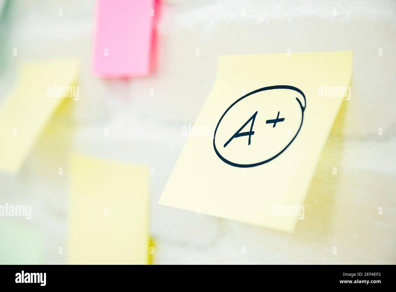 Eine Plus-Note auf Notizblock Papier an der Wand geschrieben Stockfoto