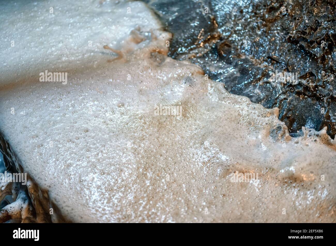 Flotationsmaschine. Von der Trennkante des Bades fließt ein grauer, verschmutzter Schaum in die Auffangschale Stockfoto