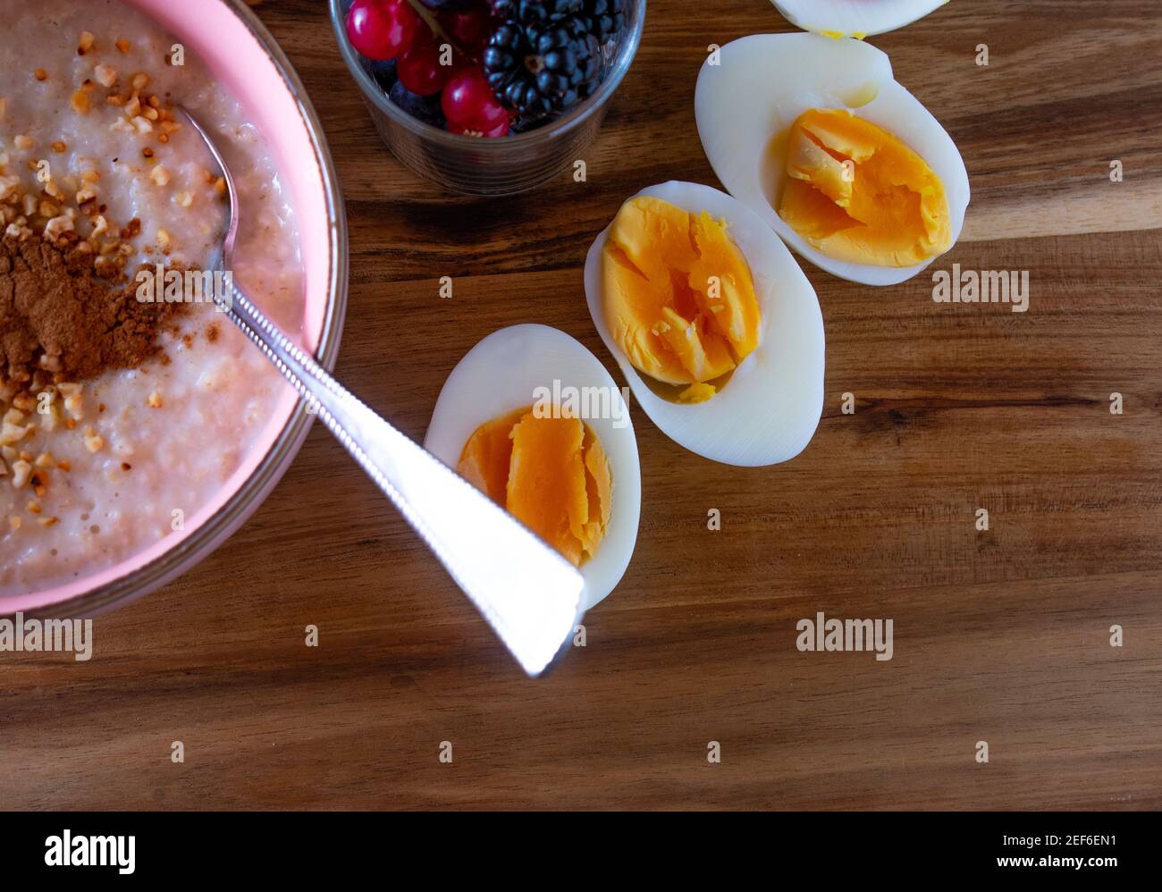 Gesundes Frühstück mit Hirsebrei, Nüssen mit frischen Beeren und gekochten Eiern auf Holzgrund mit Kopierplatz serviert Stockfoto