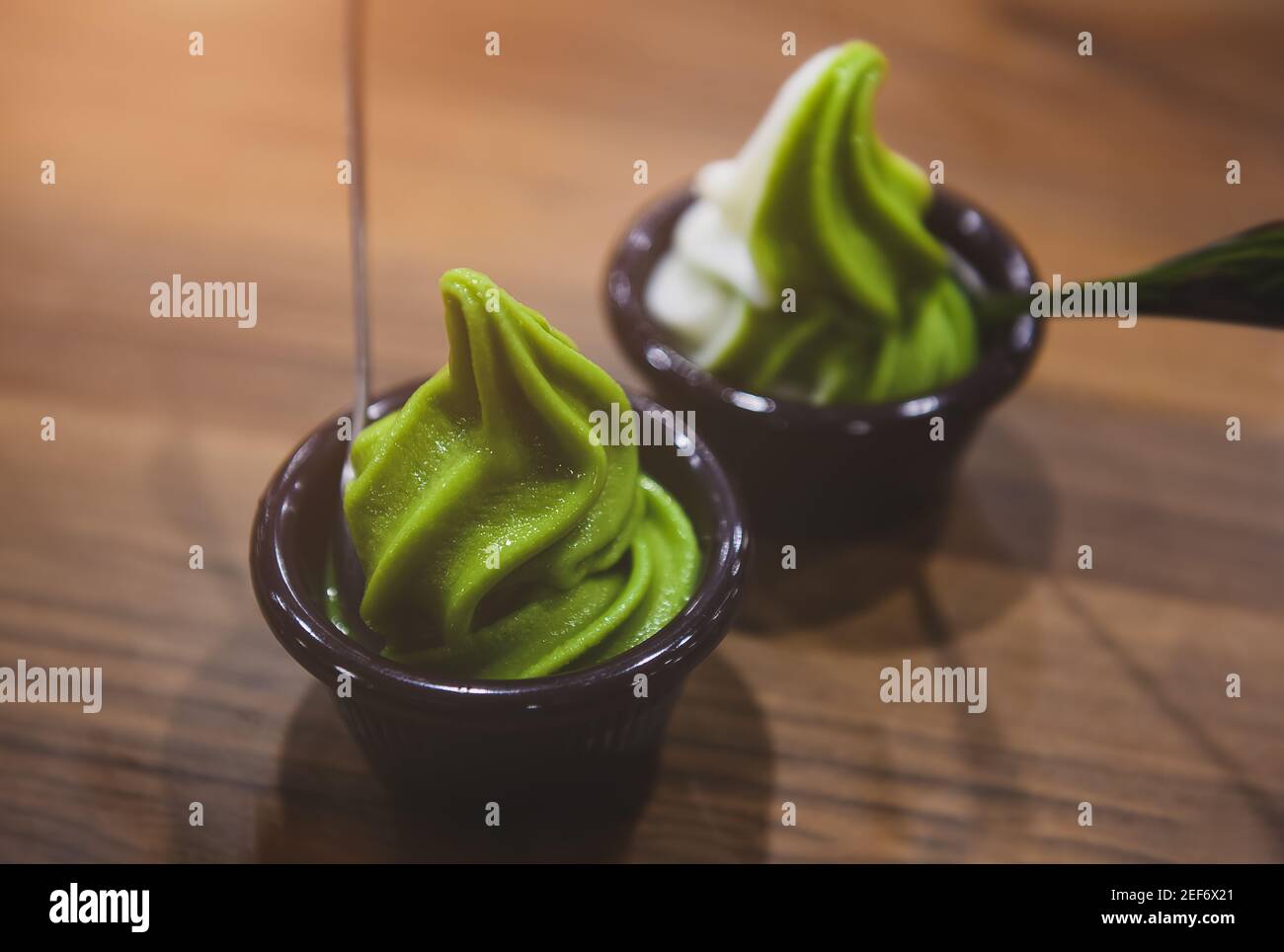 Matcha-Grüntee-Eis in einer Tasse auf einem Holztisch mit geringer Beleuchtung. Stockfoto