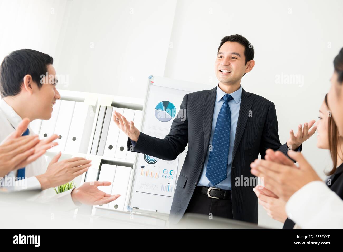 Kollegen, die einem Besprechungsleiter während des Gesprächs Beifall geben Macht eine Präsentation Stockfoto