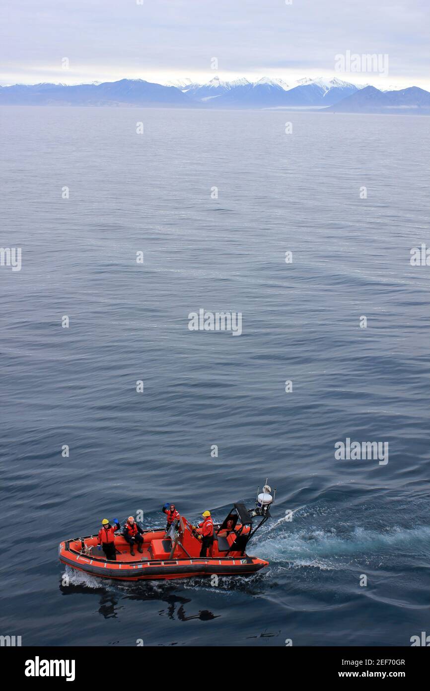 Canadian Coast Guard Crew von der CCGS Amundsen auf einem Zodiac am Pond Inlet mit den Bergen von Bylot Island Ist die Entfernung Stockfoto