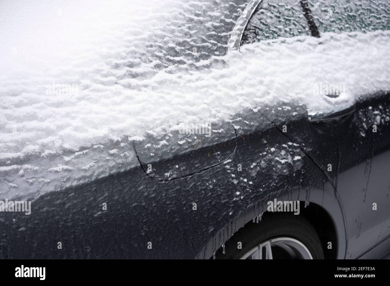Nahaufnahme der gefrorenen Gasabdeckung und des Türgriffs eines Autos auf der Straße nach einem Wintersturm von Schnee und eiskalten Regen. Stockfoto