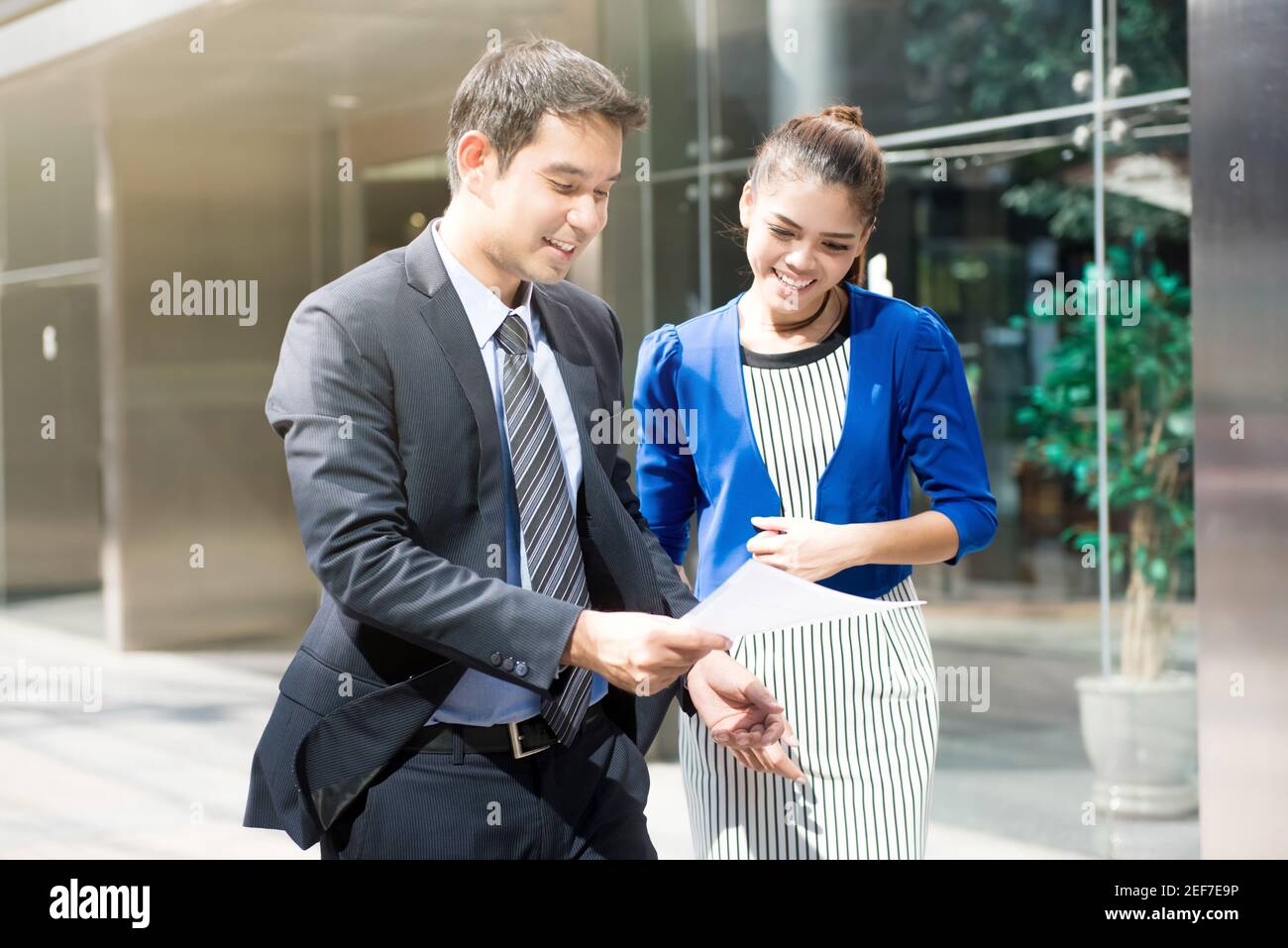 Asiatische Geschäftsleute diskutieren Dokument beim Gehen im Freien vor Des Bürogebäudes Stockfoto