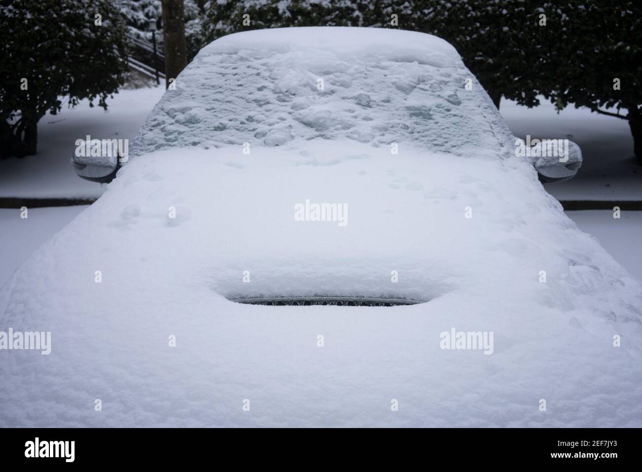 Vorderansicht eines gefrorenen Sportwagens auf den Straßen nach einem Wintersturm von Schnee und eiskalten Regen. Stockfoto