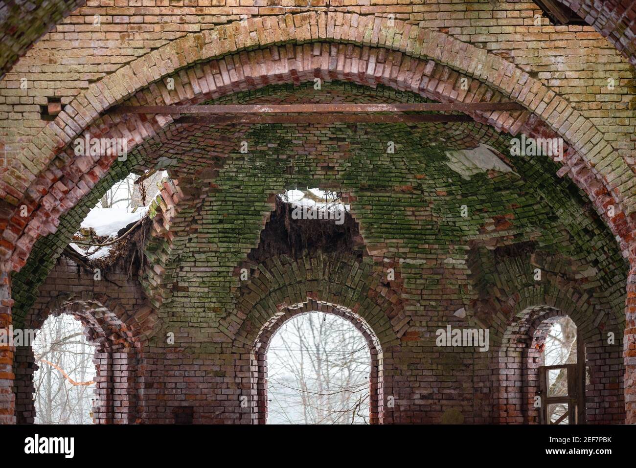 Alte Steinfenster im alten russischen Stil. Vintage Wände einer Kirche mit abblätternden Ziegeln in Russland. Bars auf einem alten Fenster. Stockfoto