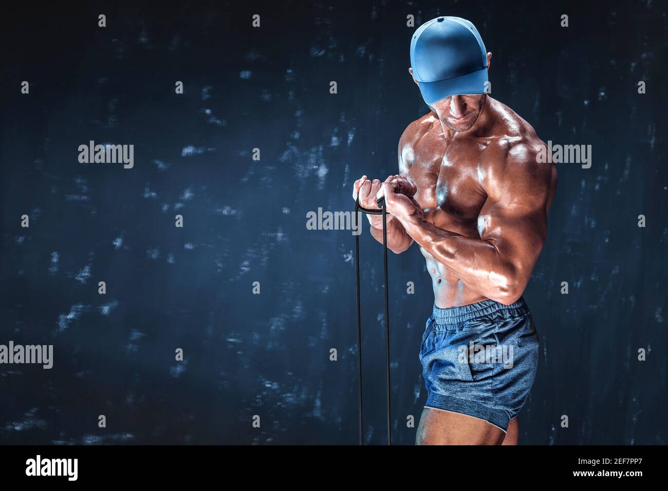 Fitness-Mann mit elastischen Bändern mit dunklem Hintergrund. Stockfoto