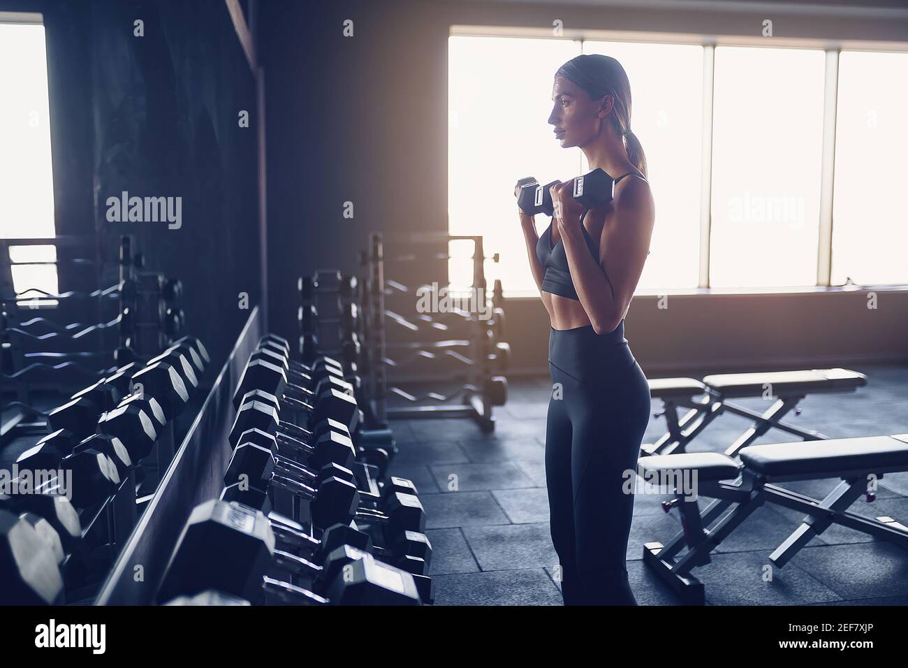 Fit Frau Training mit Hanteln tun Übung für Bizeps Muskel in der Turnhalle. Stockfoto