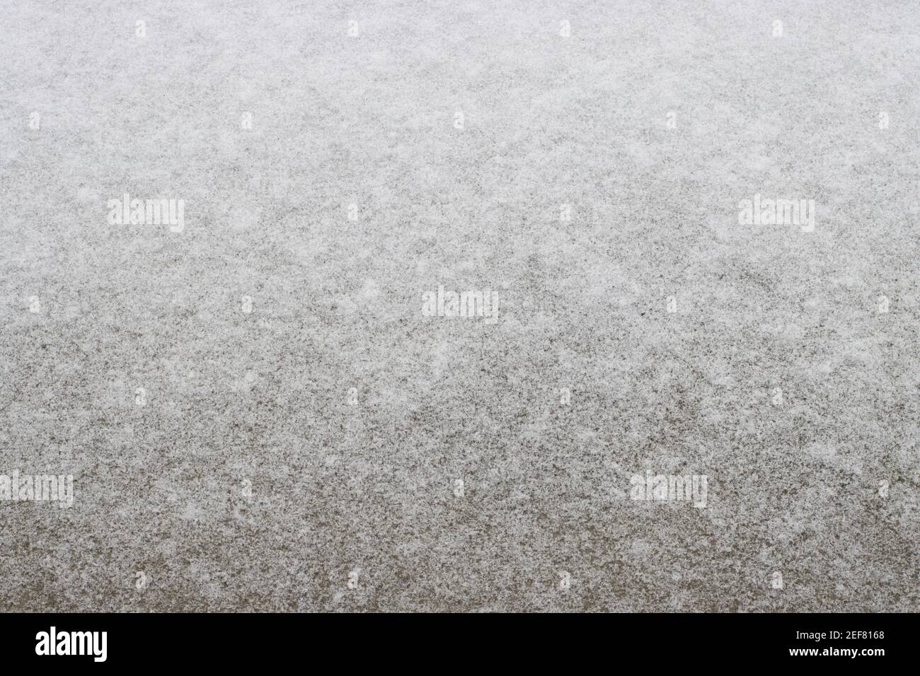 Eine dünne Schneeschicht auf dem Betondeck. Stockfoto