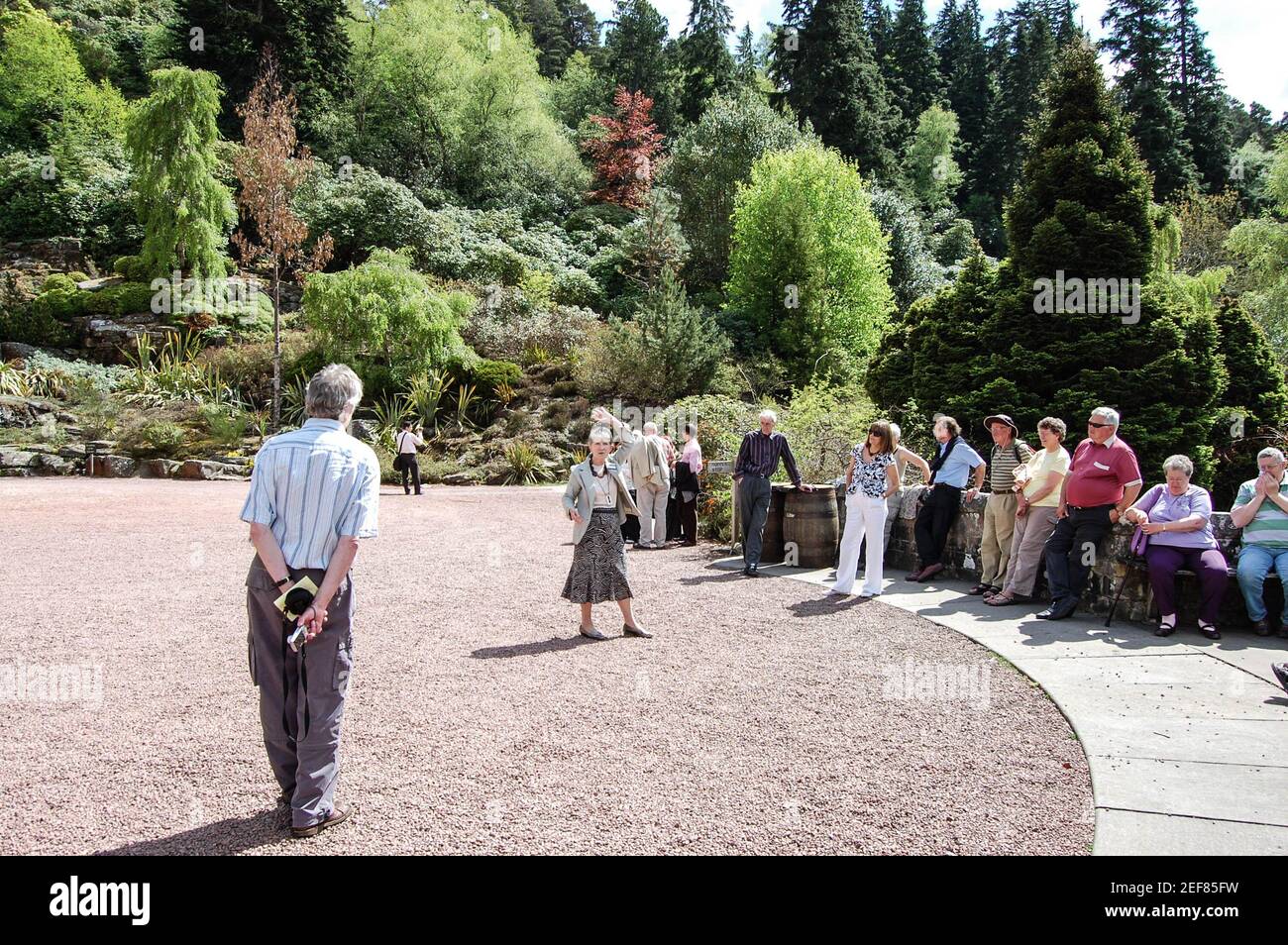 Cragside House and Gardens Rothbury wartende Leute Reiseleiter Tourist Tourist Kies Mauern Bäume vor der sonnigen, heißen Mann Lady Stockfoto